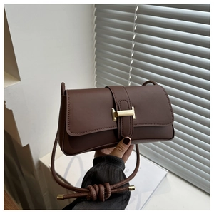 Detail of a brown PU leather baguette bag with a gold H-clasp and knotted strap detail