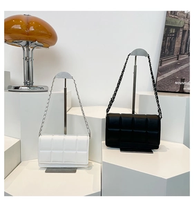 Detail of quilted leather bags with chain straps in black and white on modern stands