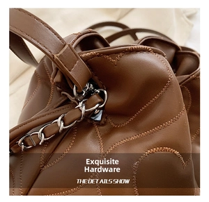 Macro shot of brown leather bag with wave stitching and polished silver chain link detail