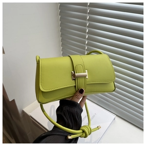 Detail of lime green leather baguette bag featuring a gold buckle and knotted strap knot