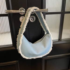 Chic crescent denim shoulder bag with white fringe trim and zipper closure for women