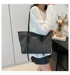 Detail of grey tote bag featuring vertical stripes and a silver bow metal buckle