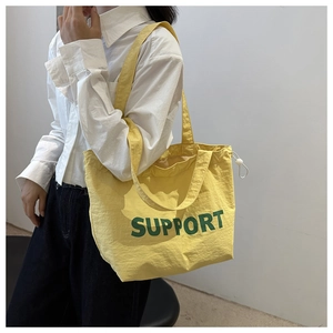 Close-up of lightweight yellow tote bag with green Support lettering and drawstring detail