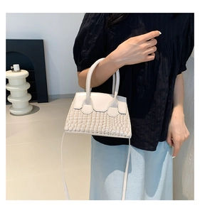 Dettaglio borsa beige in pelle a stampa coccodrillo con manico tondo e tracolla staccabile