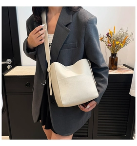 Detail of creamy white bucket bag with pebble leather texture on grey blazer