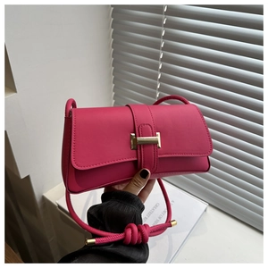 Detail of fuchsia rectangular baguette bag featuring metallic lock and knotted strap