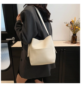 Detailed view of cream bucket bag with lychee texture and large front pocket