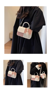 Detail view of the contrast color square bag showing top handle and adjustable shoulder strap