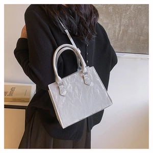 Model view of grey wrinkled texture shoulder bag with rectangular structure and hand straps