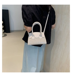 Dettagli di una borsa a tracolla beige crema con trama a coccodrillo e manico superiore