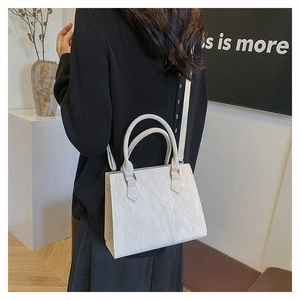 Detailed view of white pleated texture tote bag with cylindrical handles on a model
