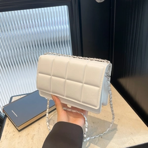 Quilted white crossbody bag with silver chain strap shown in a modern minimalist setting