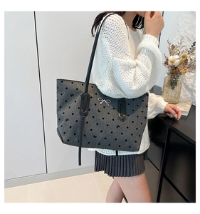 Close-up of dark grey tote bag featuring polka dot patterns and metallic bow detail