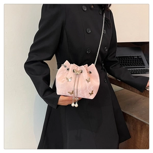 Detailed view of pink drawstring bucket bag with silver metal butterflies and pearl charms