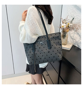 Detail of grey tote bag featuring black polka dots and silver bow buckle on the strap