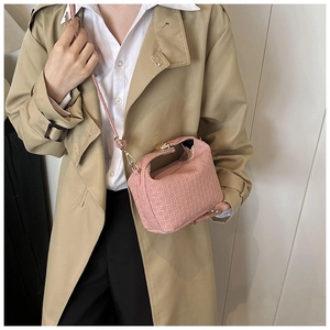 Close-up of a pink embossed crossbody bag featuring a golden buckle and slim strap