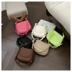 Flat lay display of colorful minimalist hobo bags with unique knotted top handles