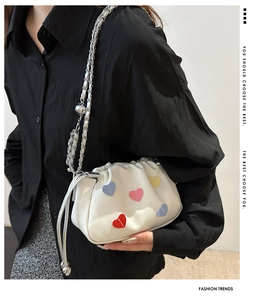 Close-up of a white cloud bag featuring colorful heart patches and a silver chain strap
