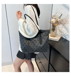 Detail of grey tote bag with black polka dots and silver metal bow ornament