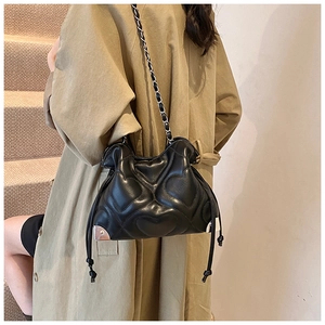 Detail of heart-quilted black shoulder bag with silver triangle corner and chain strap