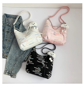 Close-up of textured shoulder bags in pink, white, and black with cloud charm details