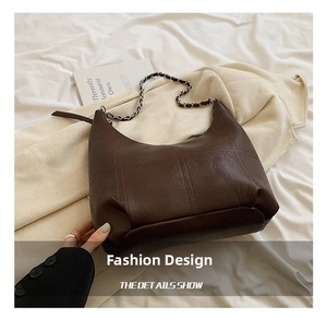 Détail du sac hobo marron foncé avec coutures matelassées et bandoulière en chaîne