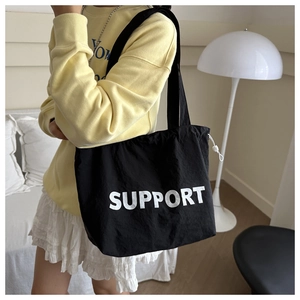 Detail view of black canvas tote bag with SUPPORT lettering and adjustable drawstring side