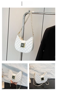 Detailed close-up of white quilted crescent bag with gold M-buckle and woven chain