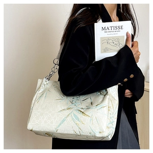 Detail of bamboo embroidery on beige tote with silk texture and silver chain strap