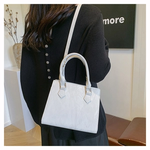 White pleated square bag on shoulder showing the elegant drape and textured PU material
