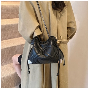 Detail of heart-quilted black leather bag with silver corner accents and chain strap