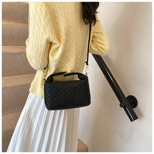 Detail of black crossbody bag featuring geometric embossed texture and gold hardware
