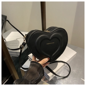 Dettaglio della borsa a tracolla nera a forma di cuore con goffratura e logo dorato