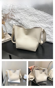 Detail of white lychee texture bucket bag with wide strap on artistic stone background