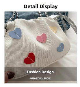 Close-up of white corduroy bucket bag with colorful leather heart patches and silver chain