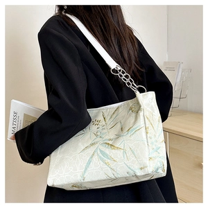 Detail of printed tote bag with bamboo leaf pattern and silver chain shoulder strap