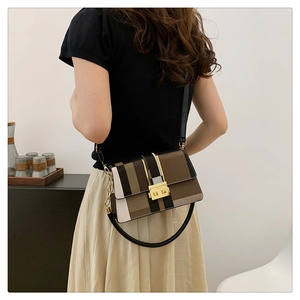 Detail of color-block striped crossbody bag with gold buckle on shoulder strap