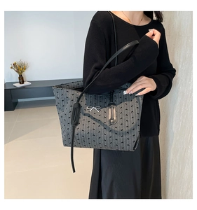 Detail of grey tote bag with black bow patterns and silver metallic bow buckle accent
