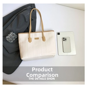Detail view of large cream tote bag with brown leather trim and office accessories