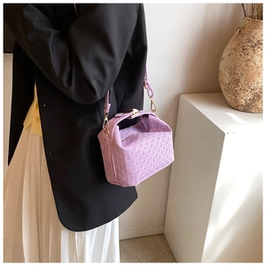 Detailed texture of lilac purple crossbody bag with geometric embossed pattern and gold hardware