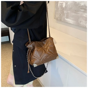 Detail of brown quilted heart pattern shoulder bag with silver chain and metal corners