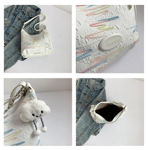 Close-up of white textured canvas bag with colorful wave embroidery and fluffy cloud charm