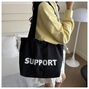 Close-up of black nylon tote bag with SUPPORT text and adjustable drawstring detail