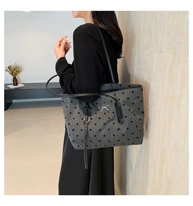 Detail of dark grey polka dot tote bag with bow embroidery worn on shoulder