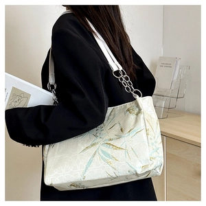 Detail of bamboo leaf embroidery on a beige tote bag with silver chain strap