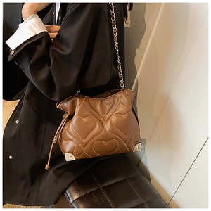 Close-up of brown heart-quilted shoulder bag with silver metal corner protectors
