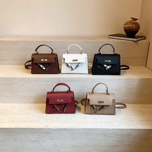 Litchi texture trapezoid handbags in five colors displayed on minimalist stone steps