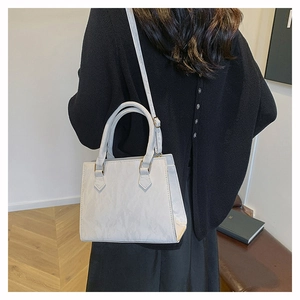 Detail of a cream structured crossbody bag with marble texture shown on a model