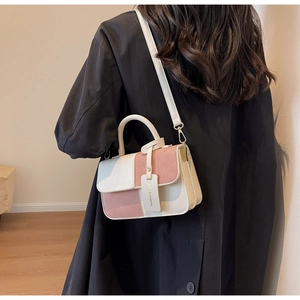 Detail of color-block flap handbag showing the contrast stitching and elegant top handle