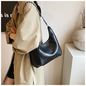 Détail du sac demi-lune noir avec bandoulière en chaîne de cuir et fermeture éclair argentée